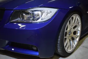 Kropla wody na wypolerowanej masce samochodu, obrazująca efekt hydrofobowy profesjonalnej powłoki ceramicznej.